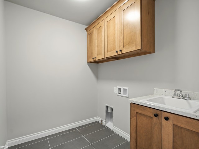 clothes washing area with cabinets, washer hookup, sink, and dark tile patterned floors