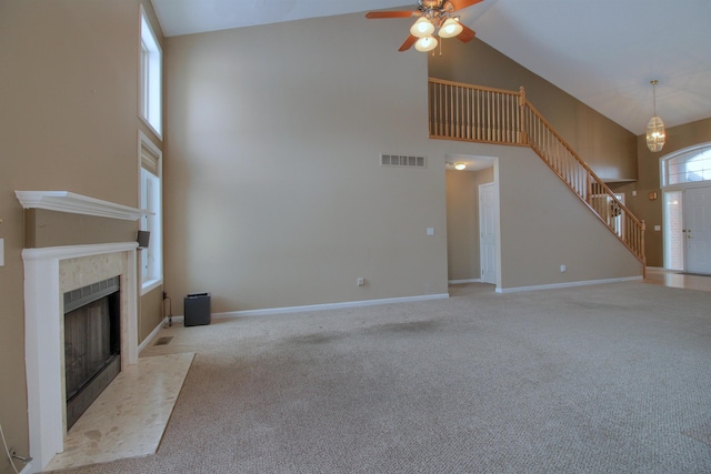 unfurnished living room with light carpet, a tile fireplace, and a high ceiling