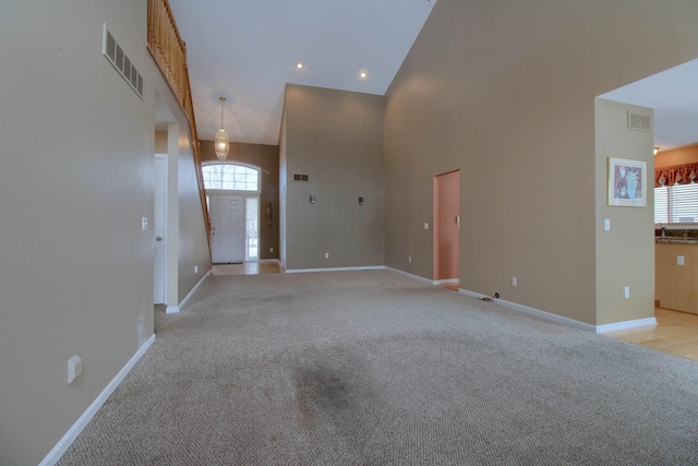 unfurnished living room with a towering ceiling and light carpet