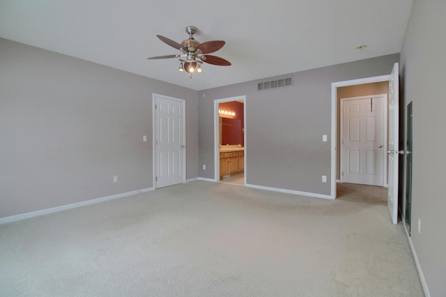 unfurnished bedroom featuring ceiling fan, light colored carpet, and ensuite bath