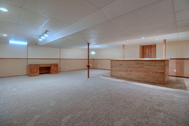 basement with a drop ceiling, light colored carpet, and bar area