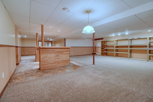 basement featuring bar, light carpet, and a drop ceiling