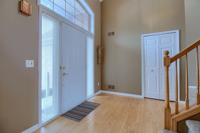 entryway with a towering ceiling and light hardwood / wood-style flooring