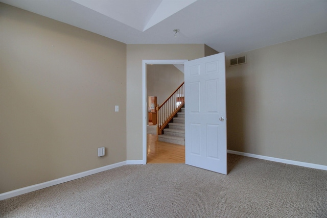 unfurnished room featuring vaulted ceiling and light carpet