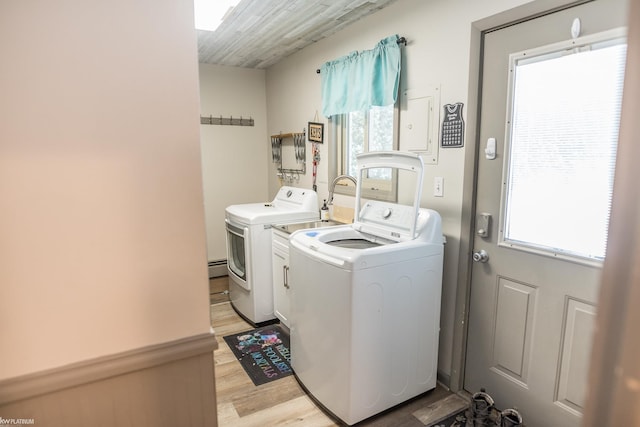 clothes washing area with cabinets, a baseboard radiator, independent washer and dryer, and light wood-type flooring