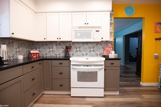 kitchen with tasteful backsplash, gray cabinetry, white cabinets, hardwood / wood-style flooring, and white appliances