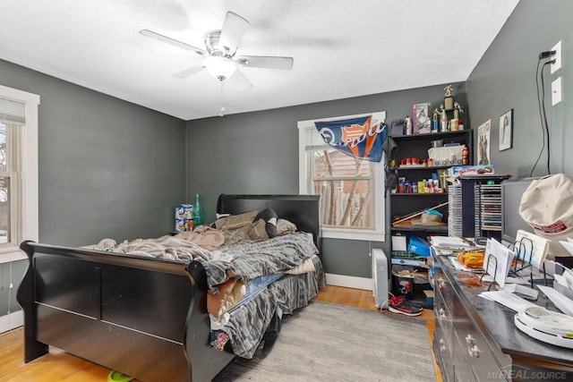 bedroom with wood-type flooring, a textured ceiling, and ceiling fan