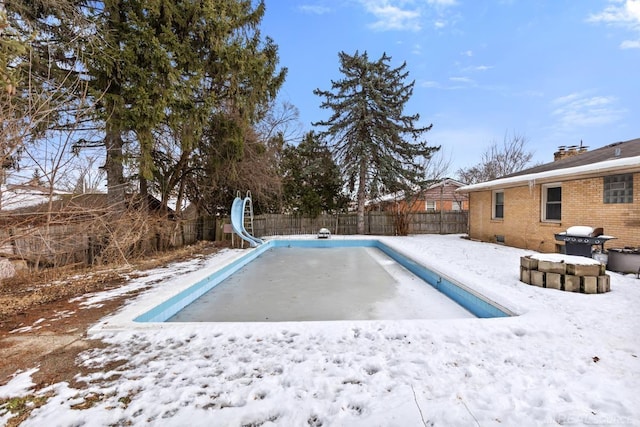 snow covered pool featuring a water slide and area for grilling