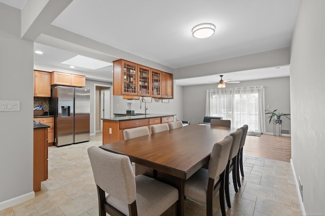 dining room with ceiling fan, a skylight, and sink