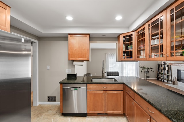 kitchen featuring stainless steel appliances, sink, and dark stone counters