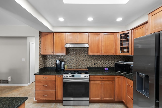 kitchen featuring backsplash, stainless steel appliances, and dark stone countertops