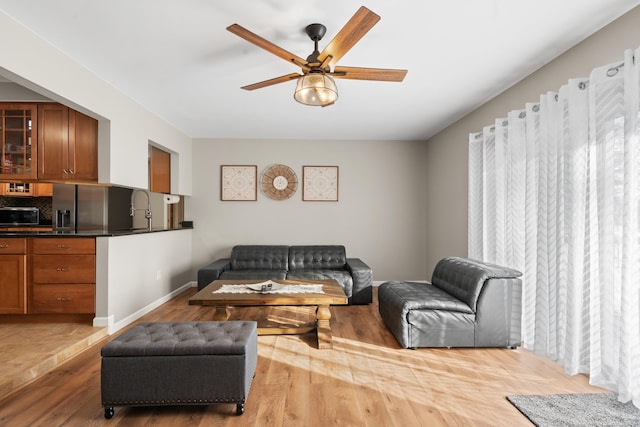 living room featuring sink, hardwood / wood-style floors, and ceiling fan