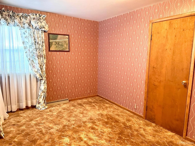 carpeted spare room featuring a baseboard heating unit