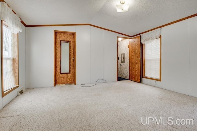 unfurnished room with crown molding, lofted ceiling, light carpet, and a textured ceiling