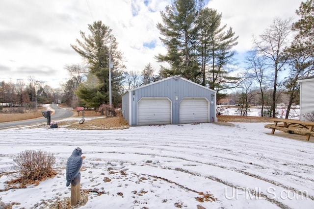 yard covered in snow featuring an outbuilding and a garage