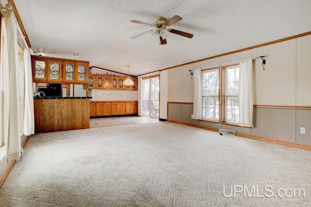 unfurnished living room with light carpet, a textured ceiling, vaulted ceiling, and a healthy amount of sunlight