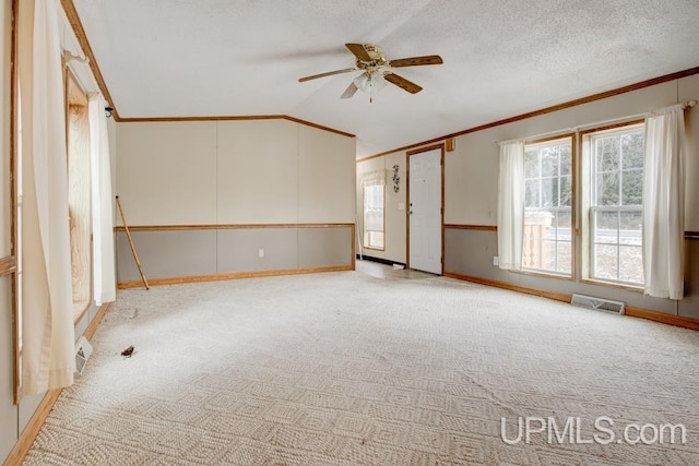 spare room with lofted ceiling, ceiling fan, crown molding, light carpet, and a textured ceiling