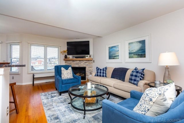 living room with hardwood / wood-style flooring and a stone fireplace