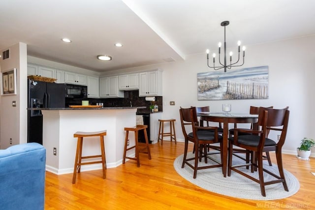 kitchen featuring decorative backsplash, light hardwood / wood-style floors, and black appliances