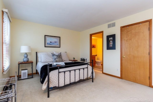 bedroom featuring light carpet and ensuite bath