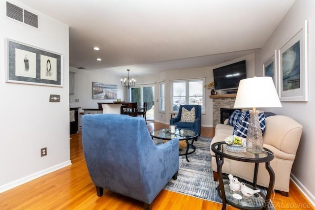 living room with a fireplace, a notable chandelier, and wood-type flooring