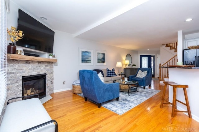 living room with a stone fireplace and wood-type flooring