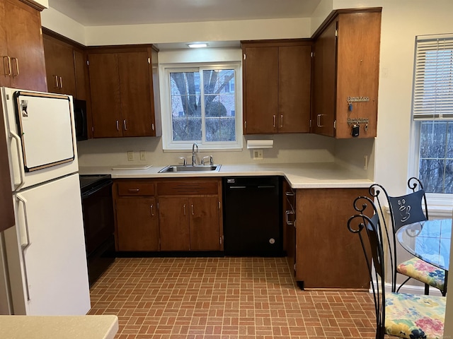 kitchen featuring sink, dark brown cabinets, and black appliances