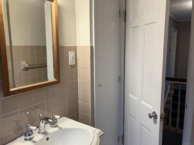 bathroom with ornamental molding, sink, and tile walls