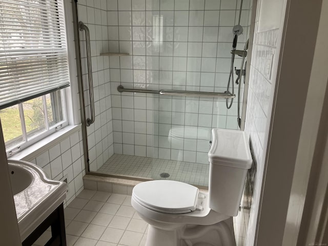 bathroom with a shower with door, tile walls, vanity, tile patterned floors, and toilet