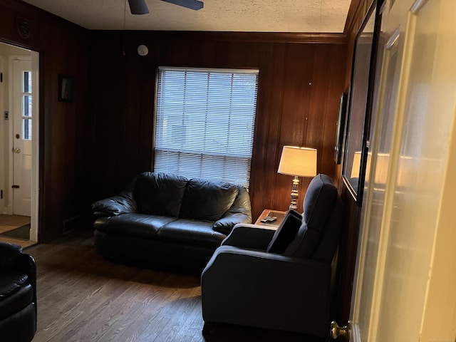 living room with hardwood / wood-style flooring, ceiling fan, and wood walls