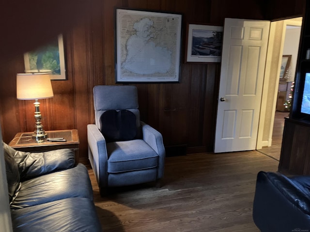 sitting room with dark wood-type flooring and wood walls