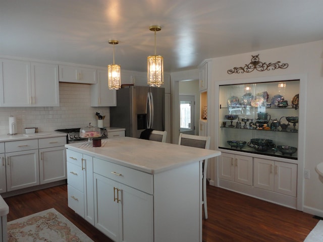 kitchen featuring dark wood-type flooring, white cabinetry, a kitchen island, pendant lighting, and stainless steel appliances