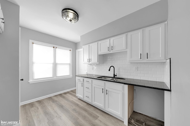 kitchen featuring white cabinetry, dark stone counters, sink, and decorative backsplash