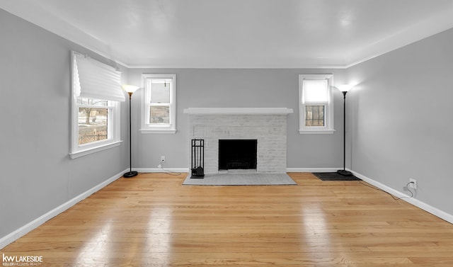 unfurnished living room with crown molding, a fireplace, and light hardwood / wood-style floors