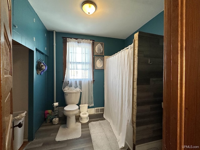 bathroom featuring hardwood / wood-style flooring, walk in shower, and toilet