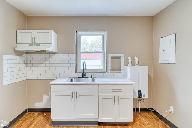 kitchen with white cabinetry, sink, electric panel, and light wood-type flooring