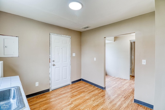 laundry area featuring sink, electric panel, and light hardwood / wood-style flooring