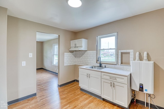 kitchen featuring sink, white cabinets, backsplash, and light wood-type flooring