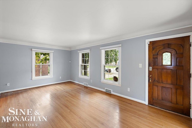 foyer with ornamental molding, plenty of natural light, and light wood-type flooring