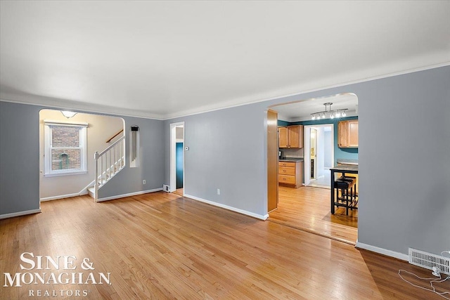 unfurnished living room featuring crown molding and light hardwood / wood-style floors