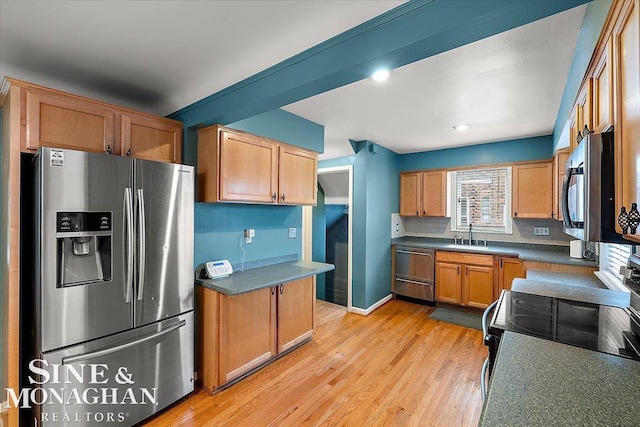 kitchen with tasteful backsplash, sink, stainless steel appliances, and light wood-type flooring