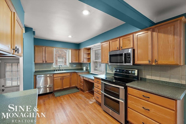 kitchen with stainless steel appliances, light hardwood / wood-style floors, sink, and backsplash