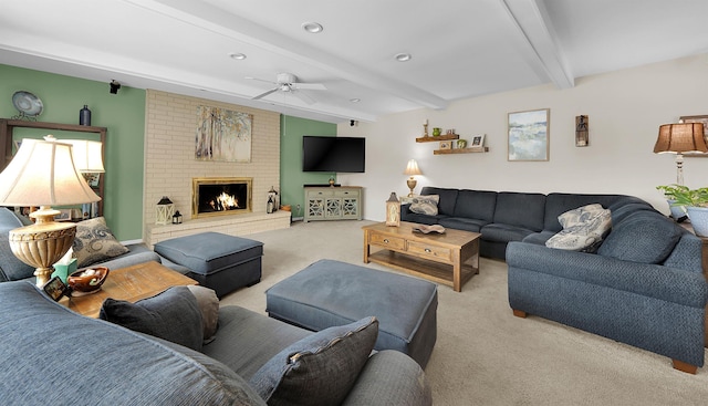 carpeted living room featuring ceiling fan, beam ceiling, and a brick fireplace