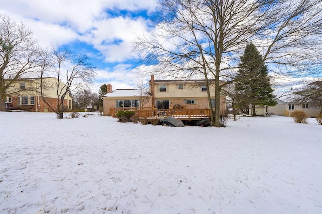 snow covered back of property with a wooden deck