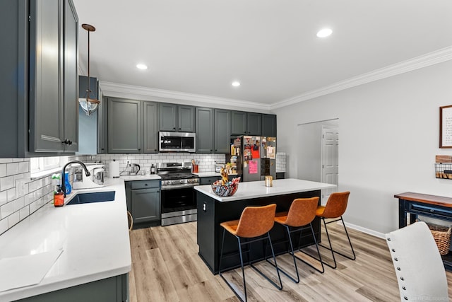 kitchen featuring sink, appliances with stainless steel finishes, gray cabinetry, a center island, and decorative light fixtures