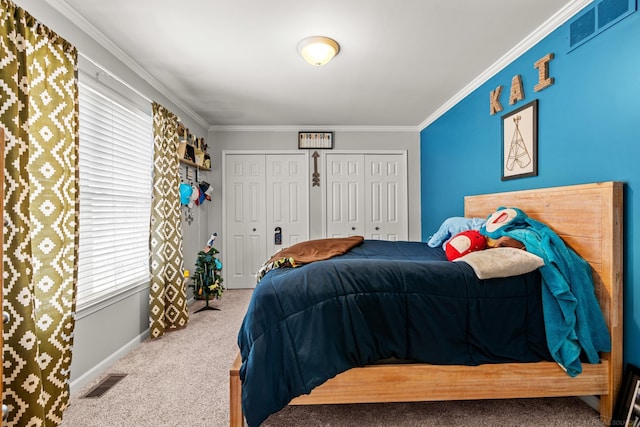 carpeted bedroom featuring ornamental molding and multiple closets