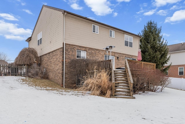 snow covered back of property with a deck