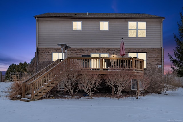 snow covered back of property with a wooden deck