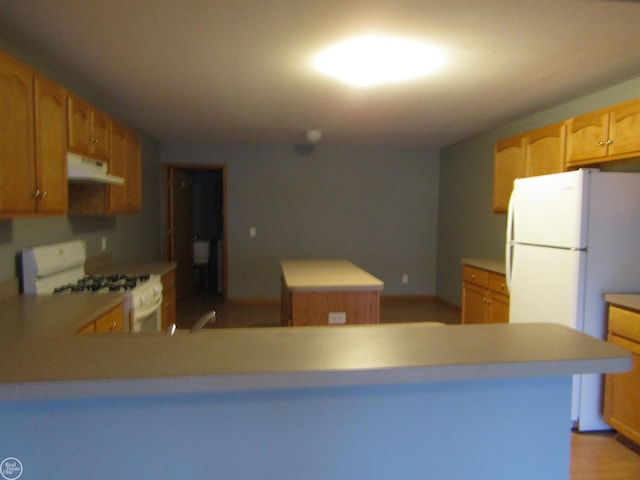 kitchen featuring white appliances, a center island, and kitchen peninsula