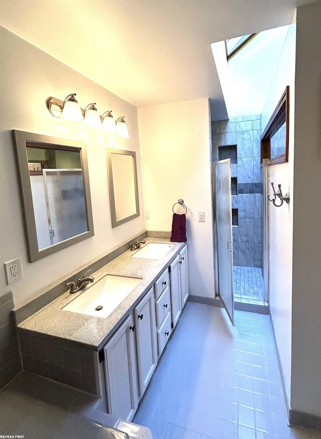 bathroom featuring vanity, tile patterned flooring, a skylight, and a tile shower